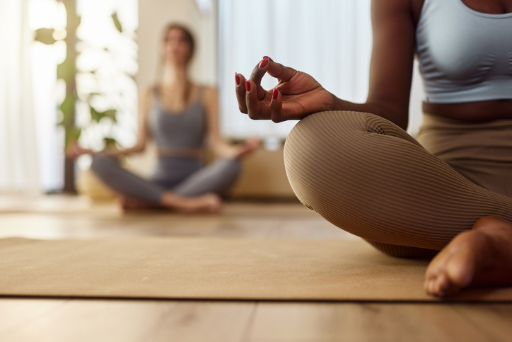 Close up of unrecognizable African American woman doing Yoga meditation exercises in Lotus position in a health club.