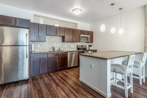 A modern kitchen with an island and bar stools in an apartment building