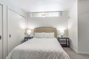 A bedroom with a large bed and night stands with lamps on either side in an apartment building