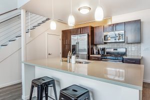 A modern kitchen with an island and bar stools in an apartment building