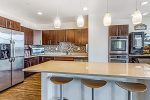 A common kitchen area with an oven, a coffee machine, sink, microwave, and fridge