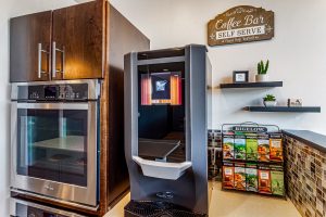 A common kitchen area with an oven and a coffee machine and rack of teas