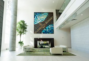 A common area in an apartment building with couches, huge modern artwork on the wall, and a gas fireplace