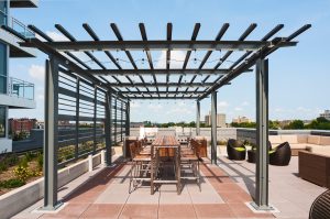 Rooftop Gardens with Grills and a long table and chairs under a trellis