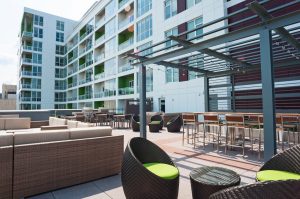 Exterior of a tall, glass building with a lower roof/balcony dining area