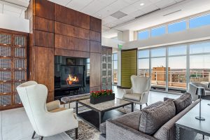 An apartment common room on the upper floor of a building with chairs and couches and a gas fireplace